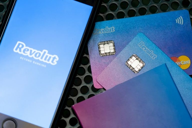 Revolut cards a laying near the phone which shows Revolut;s logo.